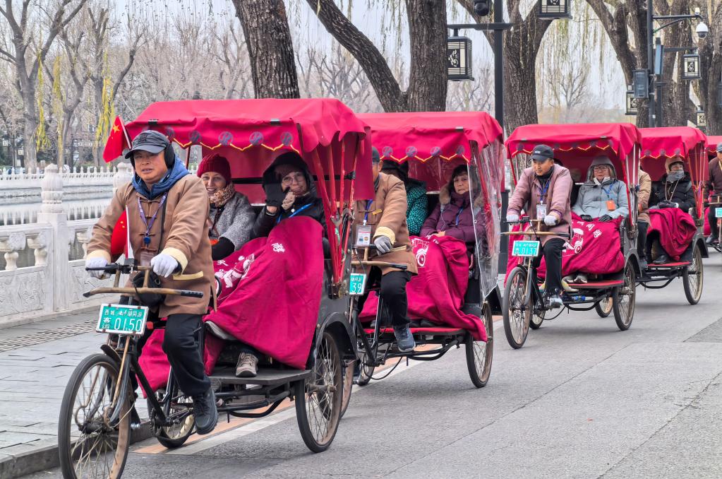 2024年12月12日，外国游客在北京什刹海乘坐人力三轮车观光。新华社记者鞠焕宗摄